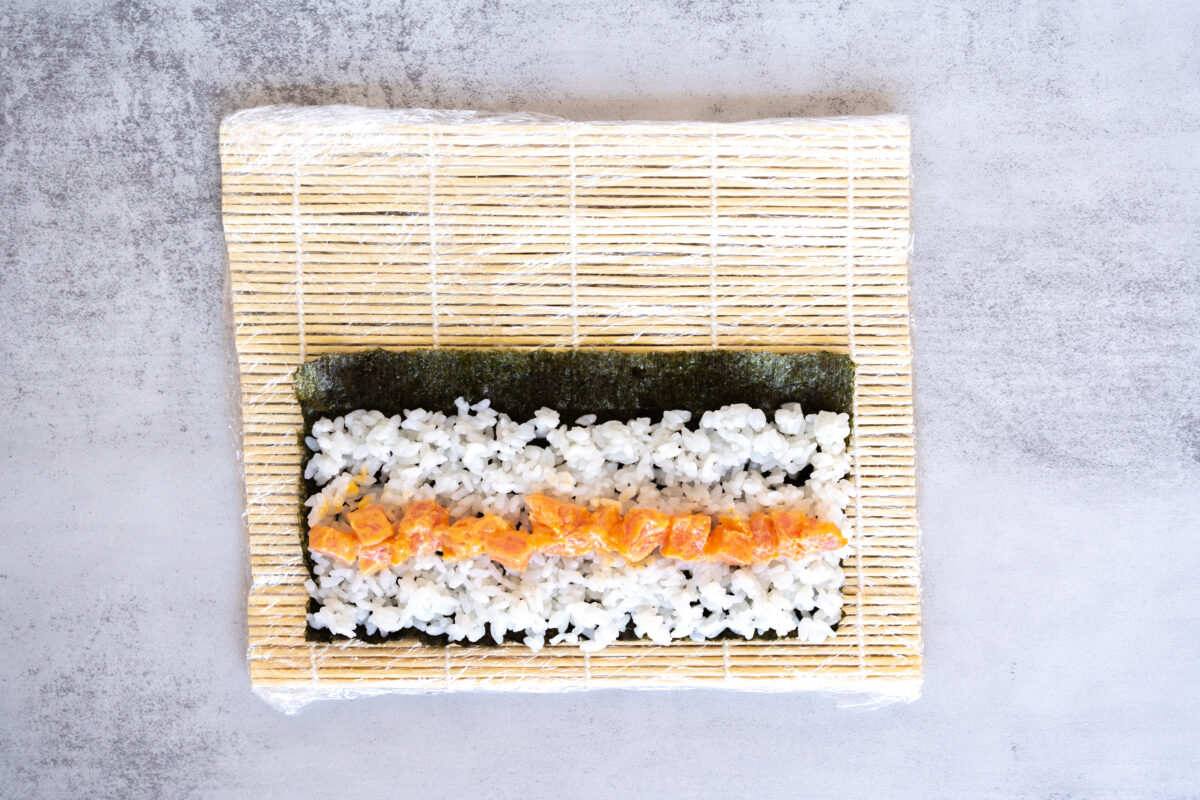 A Spicy Tuna Roll, ready to be rolled up on the sushi mat.