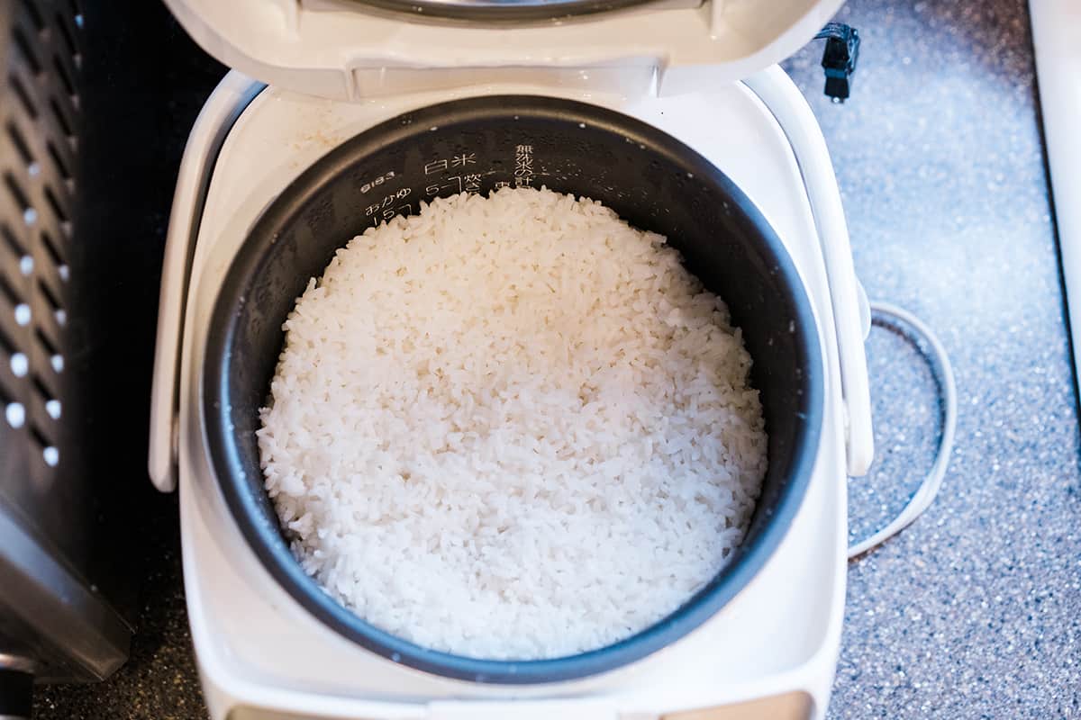 Nasi bulir pendek Jepang dimasak dan duduk di penanak nasi Jepang.