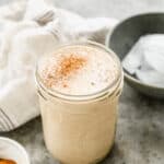 A homemade Vanilla Protein Shake in a mason jar and sprinkled with cinnamon.