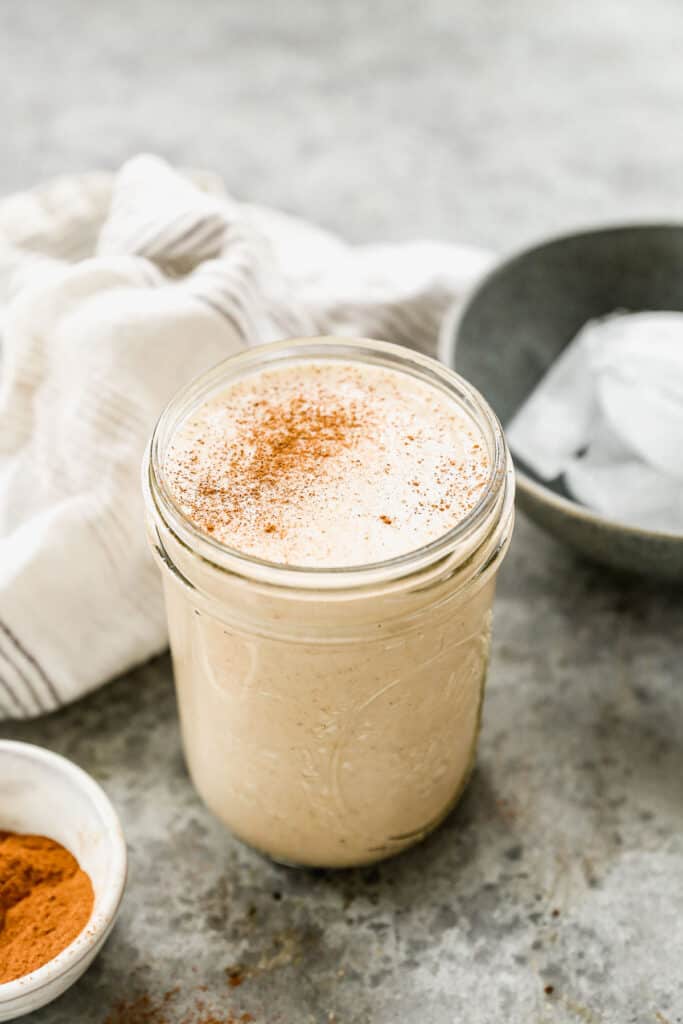 A homemade Vanilla Protein Shake in a mason jar and sprinkled with cinnamon.