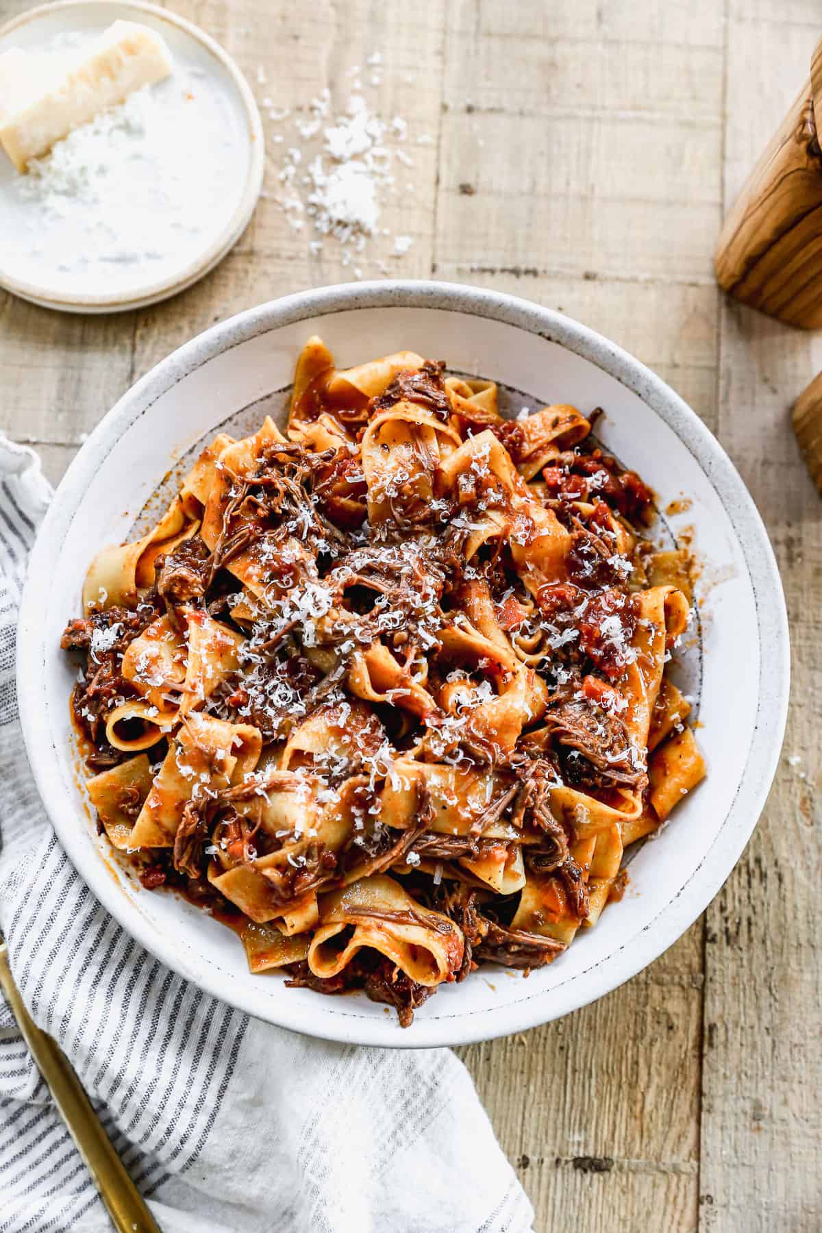 A bowl filled with easy Short Rib Ragu, sprinkled with fresh parmesan cheese.