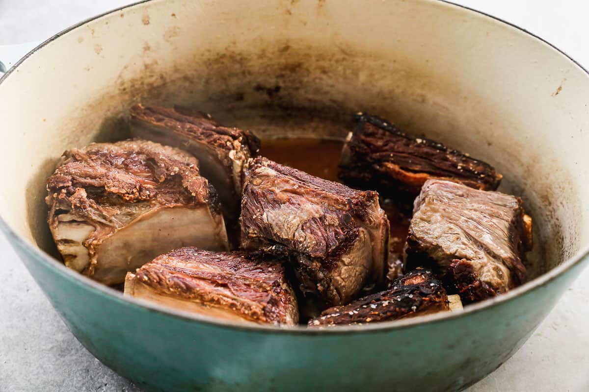 Beef short ribs being seared in a dutch oven pot to make Short Rib Ragu.
