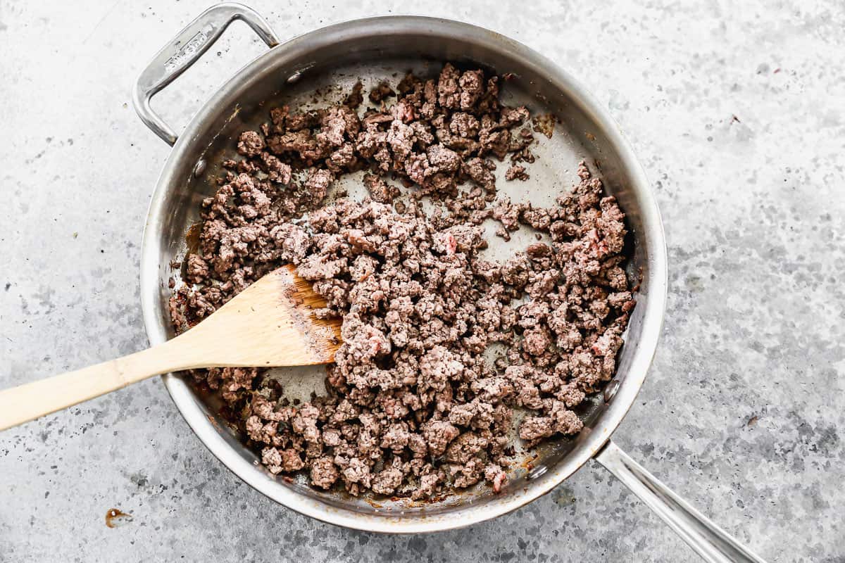 Cooked ground beef in a large stainless steel pan. 
