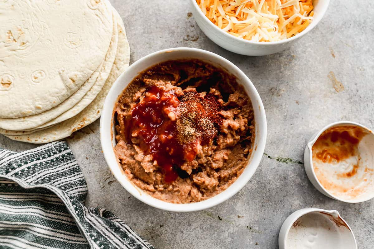 A bowl of refried beans with salsa and seasoning on top to add more flavor.