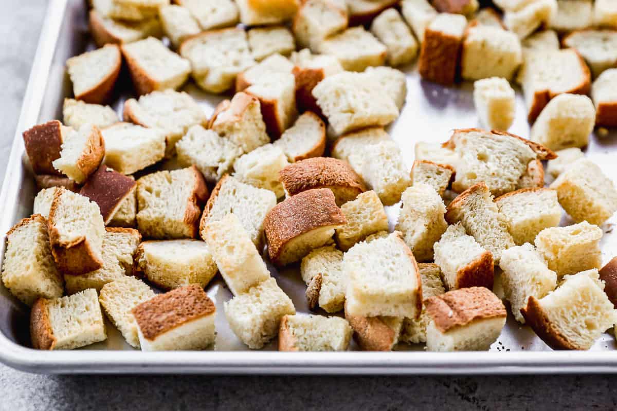 Dried bread cubes on a baking sheet to make homemade bread pudding. 