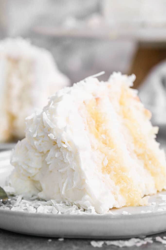 A slice of homemade Coconut Cake with pineapple filling on a plate ready to serve.