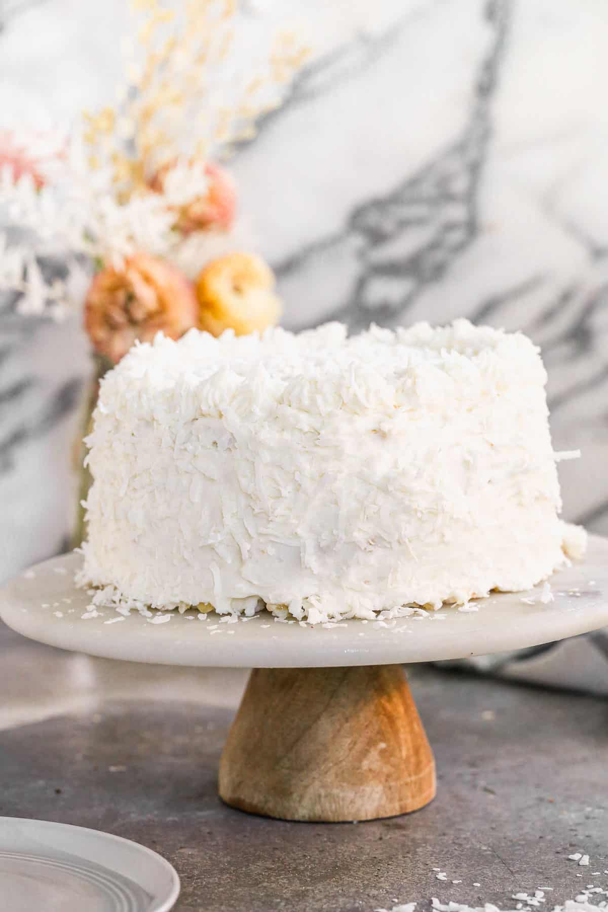 An easy Coconut Cake on a cake stand, ready to slice and enjoy.