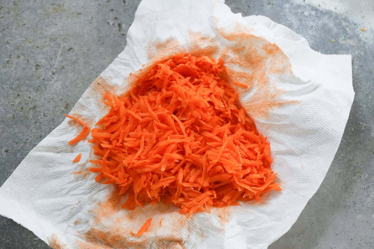 A paper towel with shredded carrots on it to make an easy carrot cake recipe.