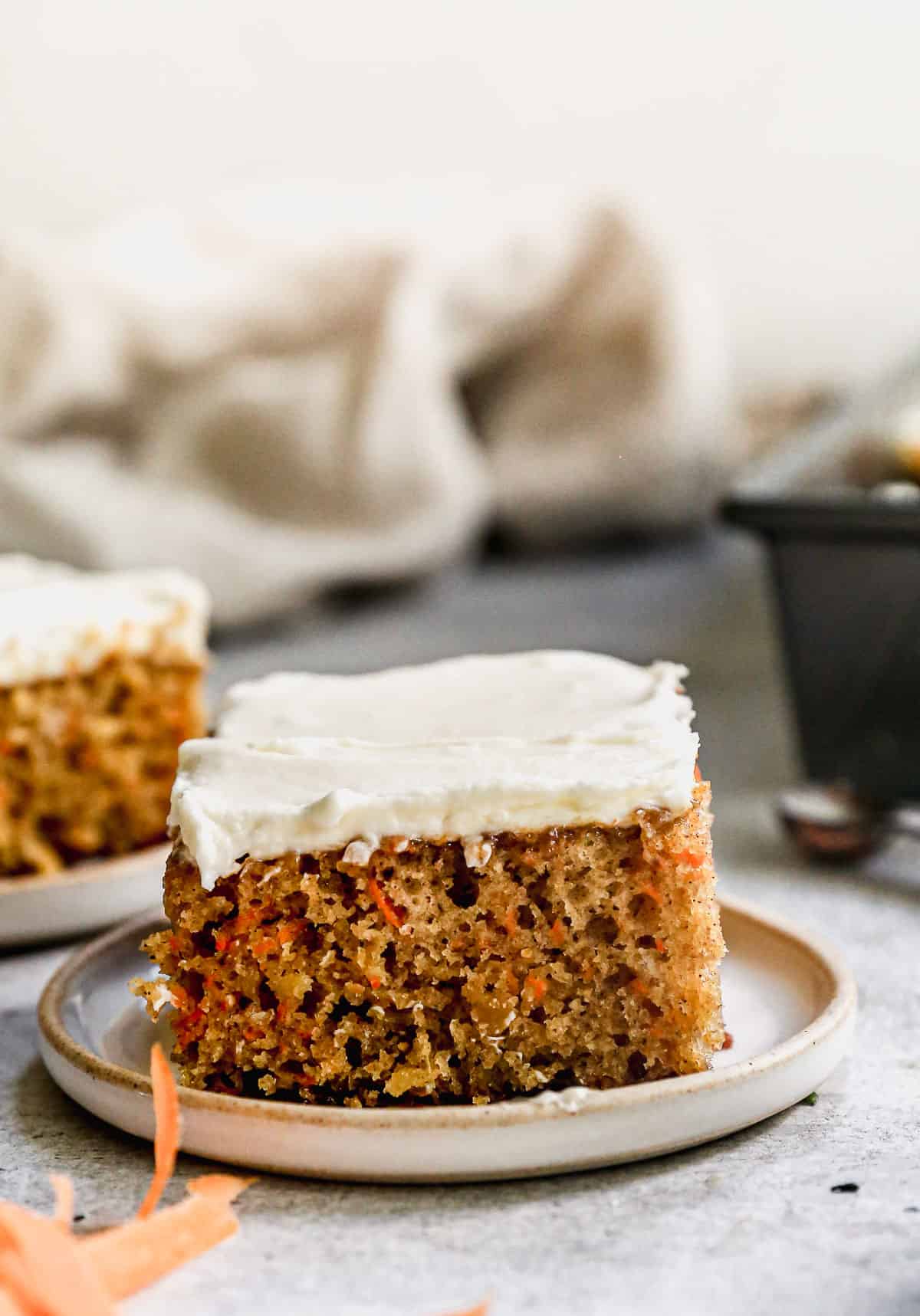 A piece of Easy Carrot Cake with whipped cream cheese frosting on a serving plate, ready to enjoy.