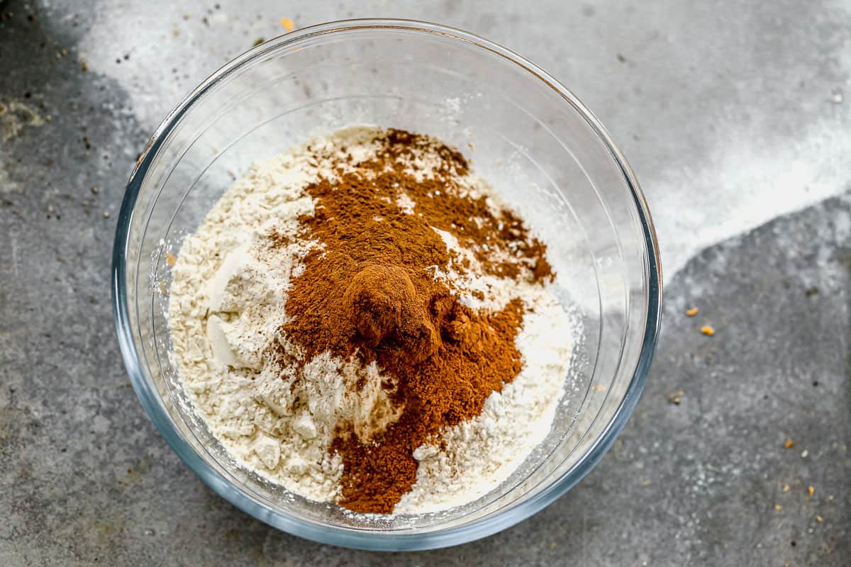 A bowl of flour, spices, salt, baking soda, and baking powder in a glass mixing bowl.