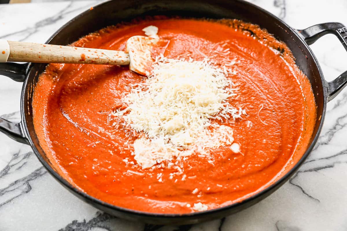 Smooth pink sauce in a saucepan with fresh parmesan cheese added on top.