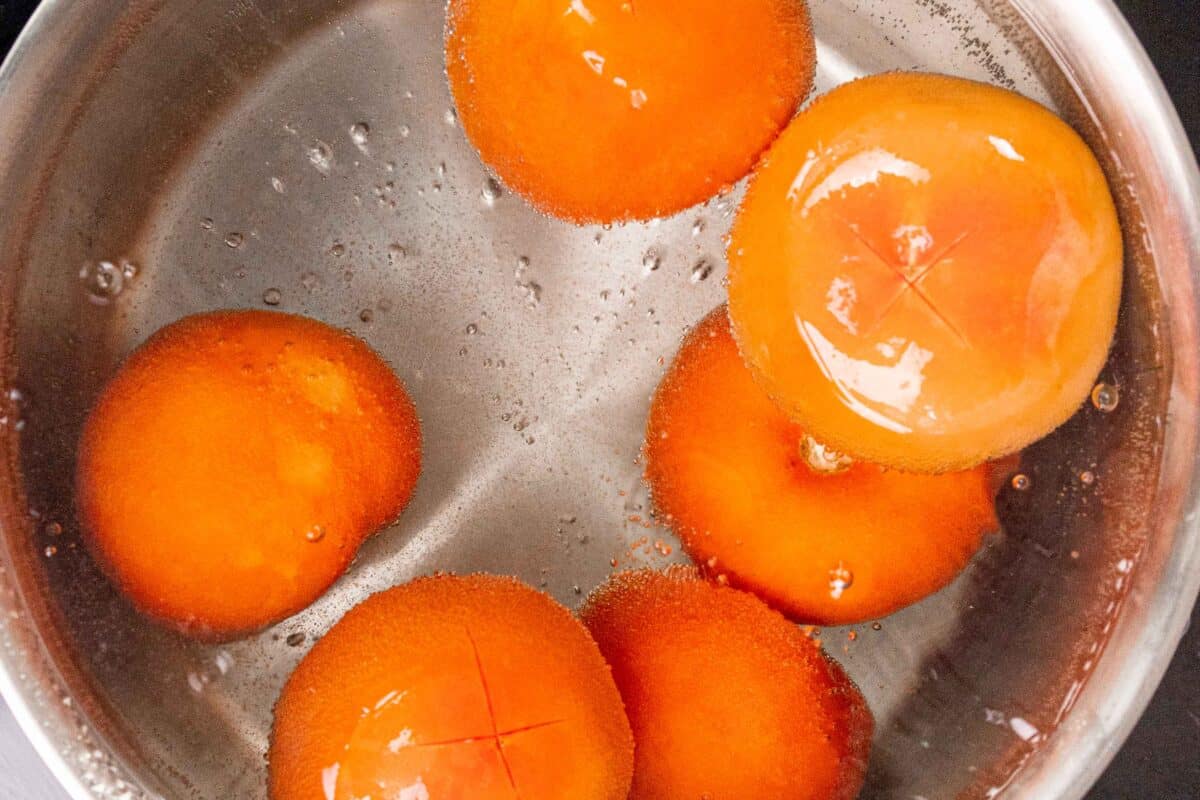 Cross cut tomatoes in a pot of boiling water.