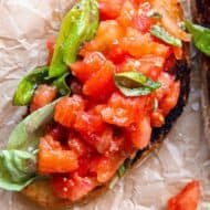 A slice of Tomato basil bruschetta with toasted artisan bread.