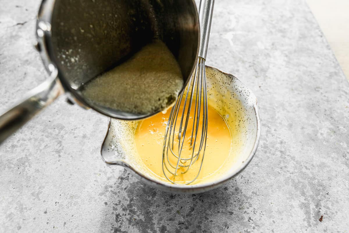 Hot melted butter being added to hollandaise sauce to temper the egg.