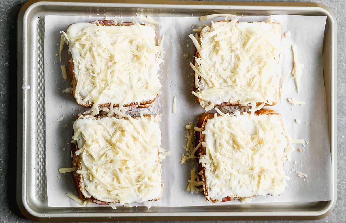 Easy Croque Madame sandwiches covered in béchamel sauce and cheese, ready to bake.
