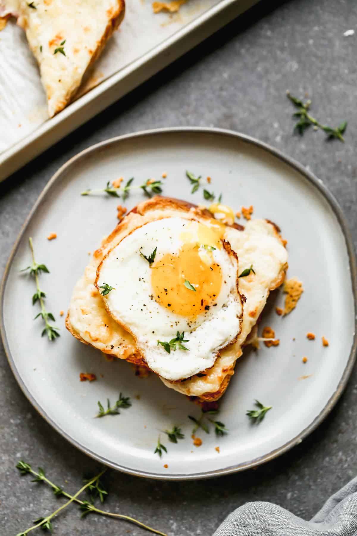 A French Croque Madame sandwich on a plate, topped with an egg.