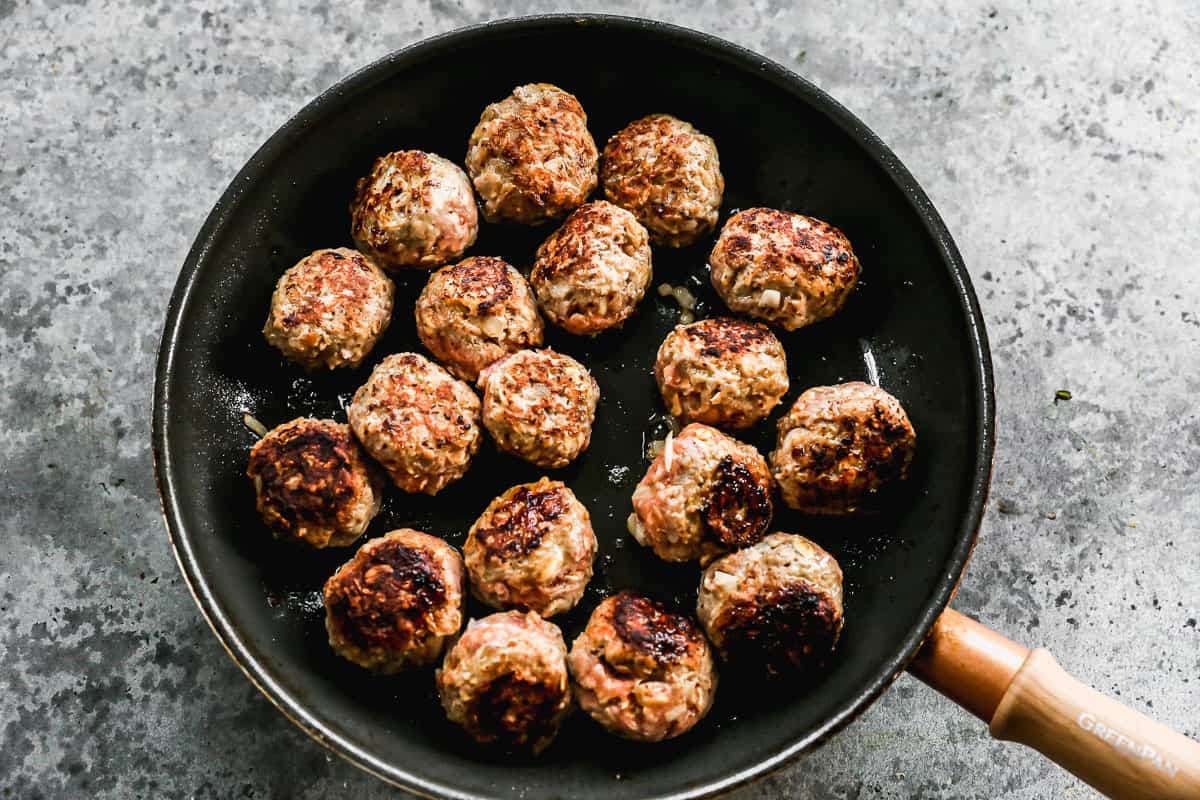 Meatballs being browned in a non-stick pan. 