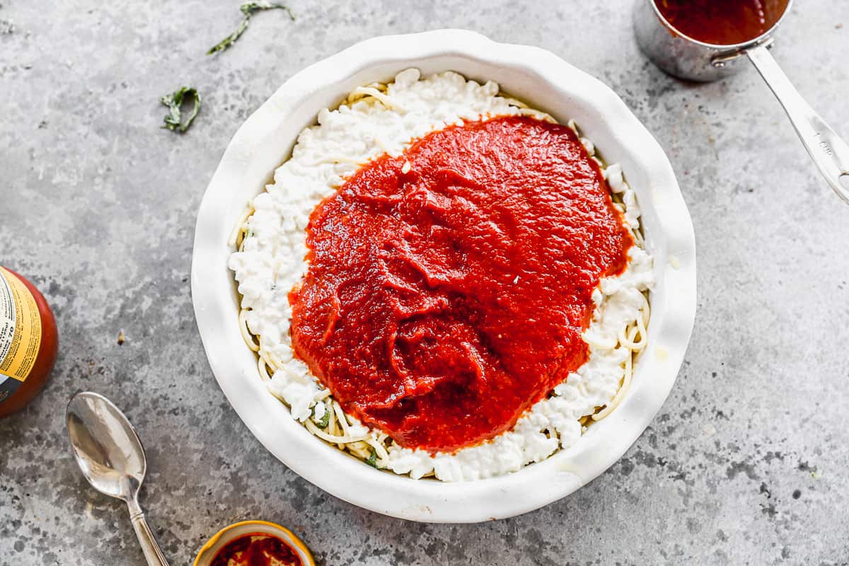 Spaghetti Sauce poured on top of a layer of cottage cheese in a pie dish to make the best Spaghetti Pie recipe.