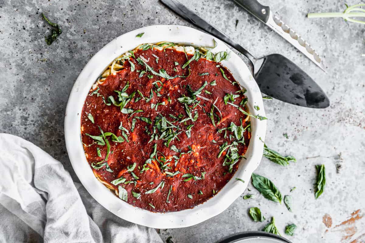 A meatless Spaghetti Pie recipe just out of the oven with fresh basil on top, ready to serve.