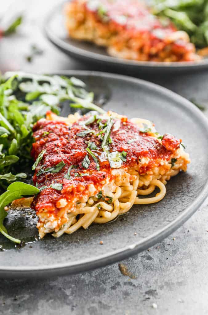 A slice of Spaghetti Pie on a plate with a green salad.