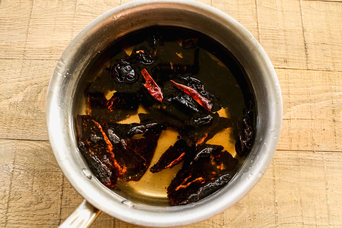 Six guajillo chiles in a saucepan covered with water to help soften them.