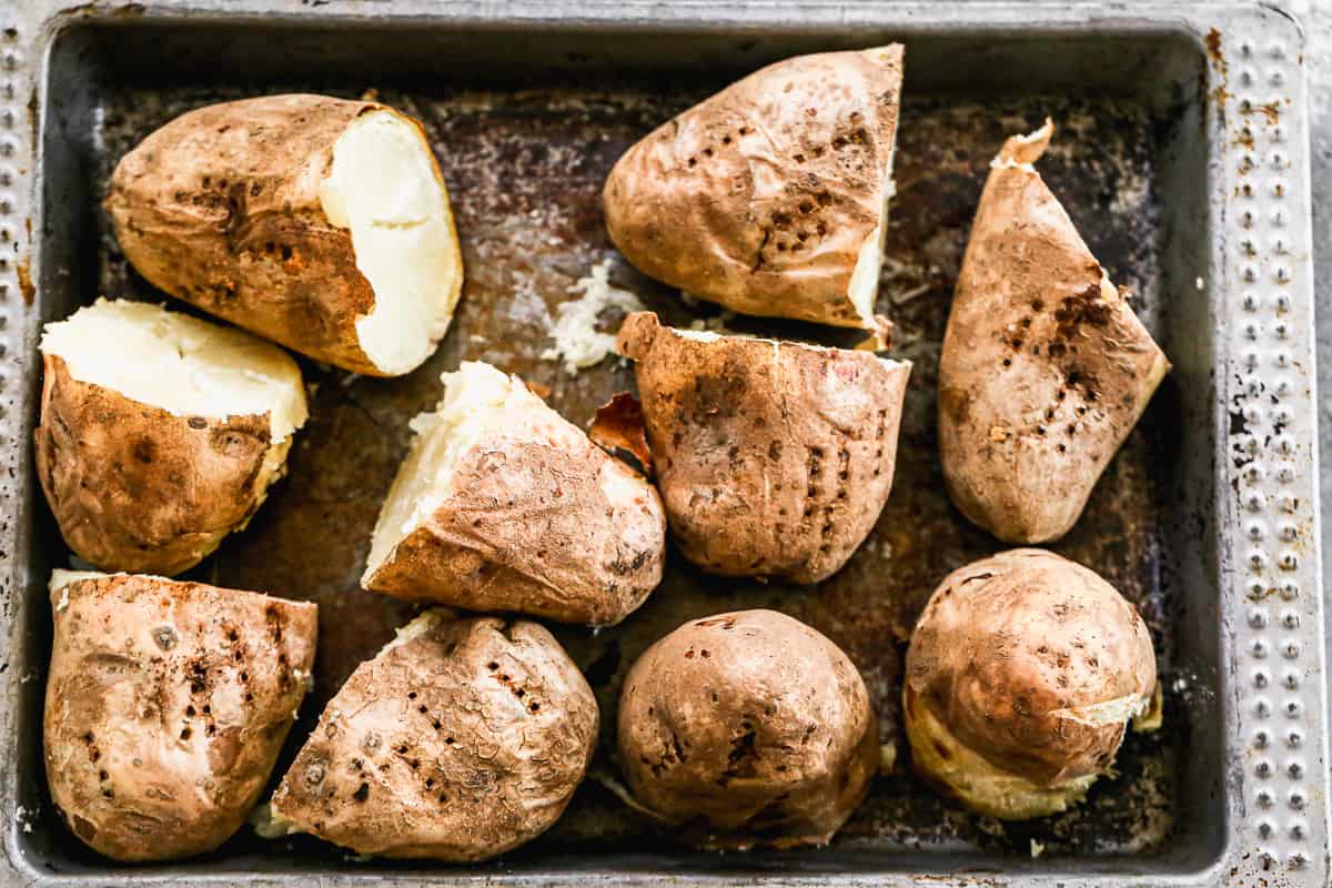 A baking sheet with baked potatoes cut in half for Baked Potato Salad.