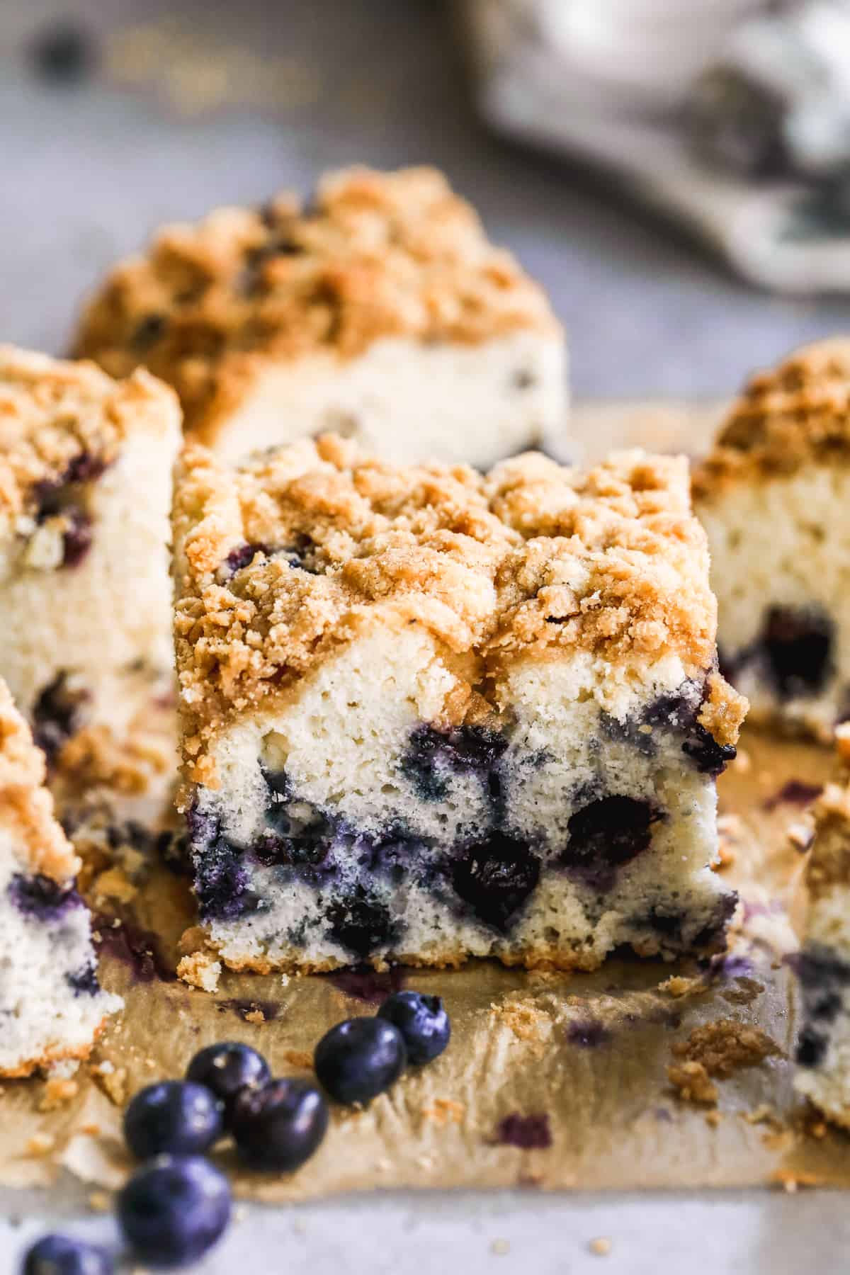 Homemade Blueberry Coffee Cake cut into squares, on a piece of parchment paper.