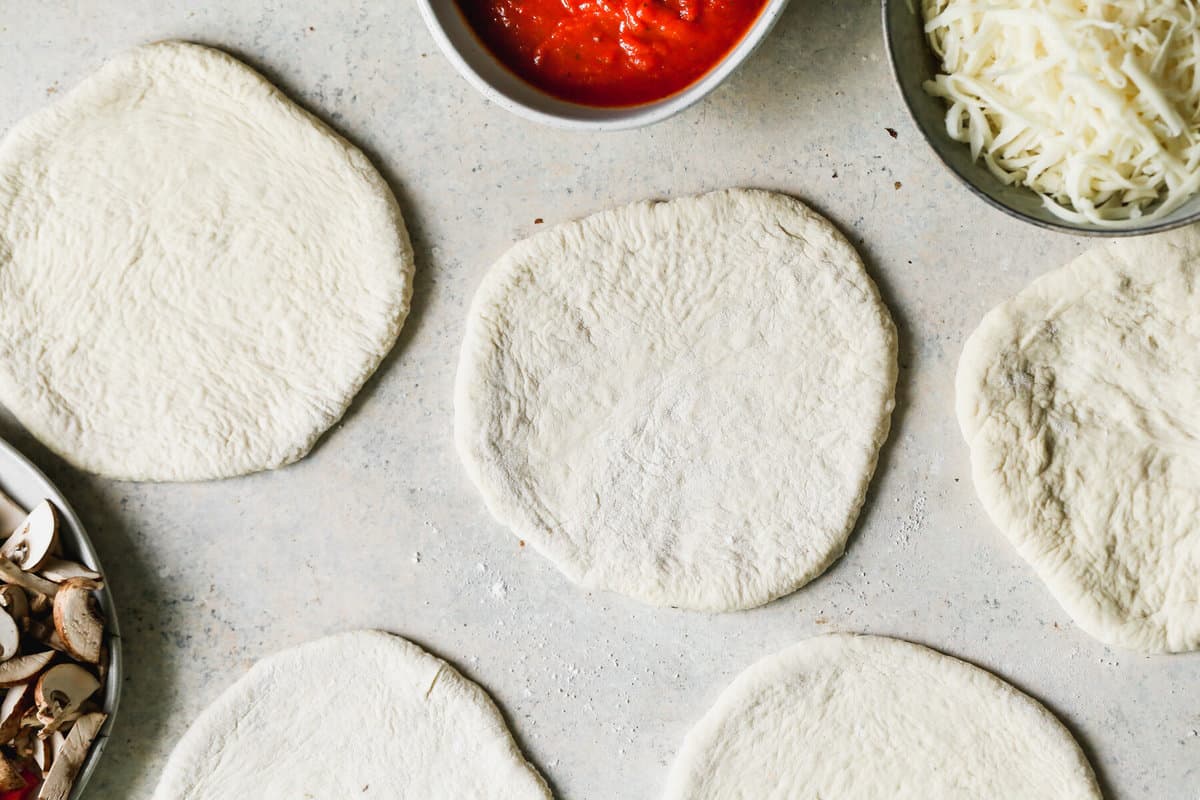 A counter filled with some circles of pizza dough rolled out to make homemade calzones.