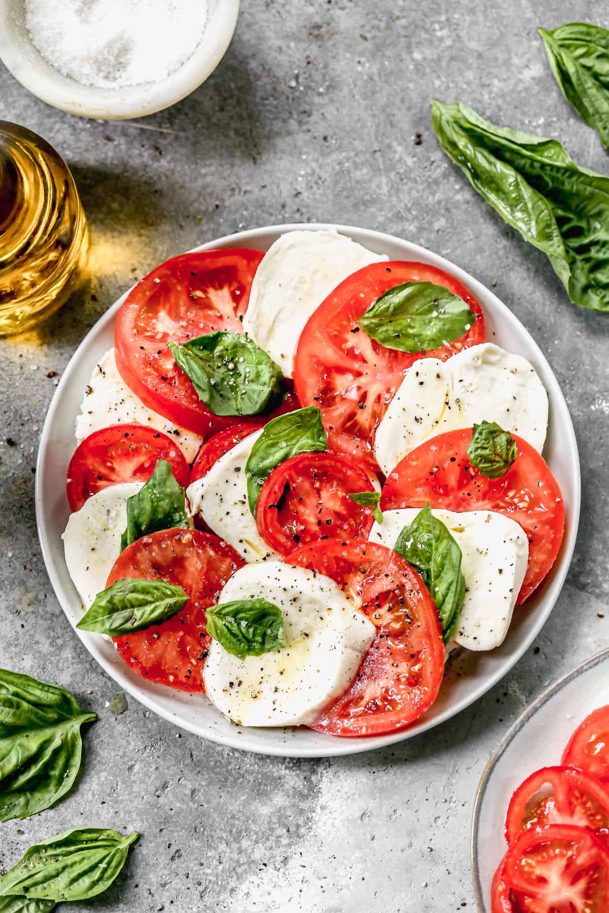 A plate of easy Caprese Salad with fresh mozzarella cheese and basil leaves.