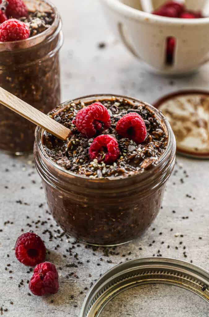 A jar filled of easy Chocolate Overnight Oats topped with fresh raspberries and cacao nibs.