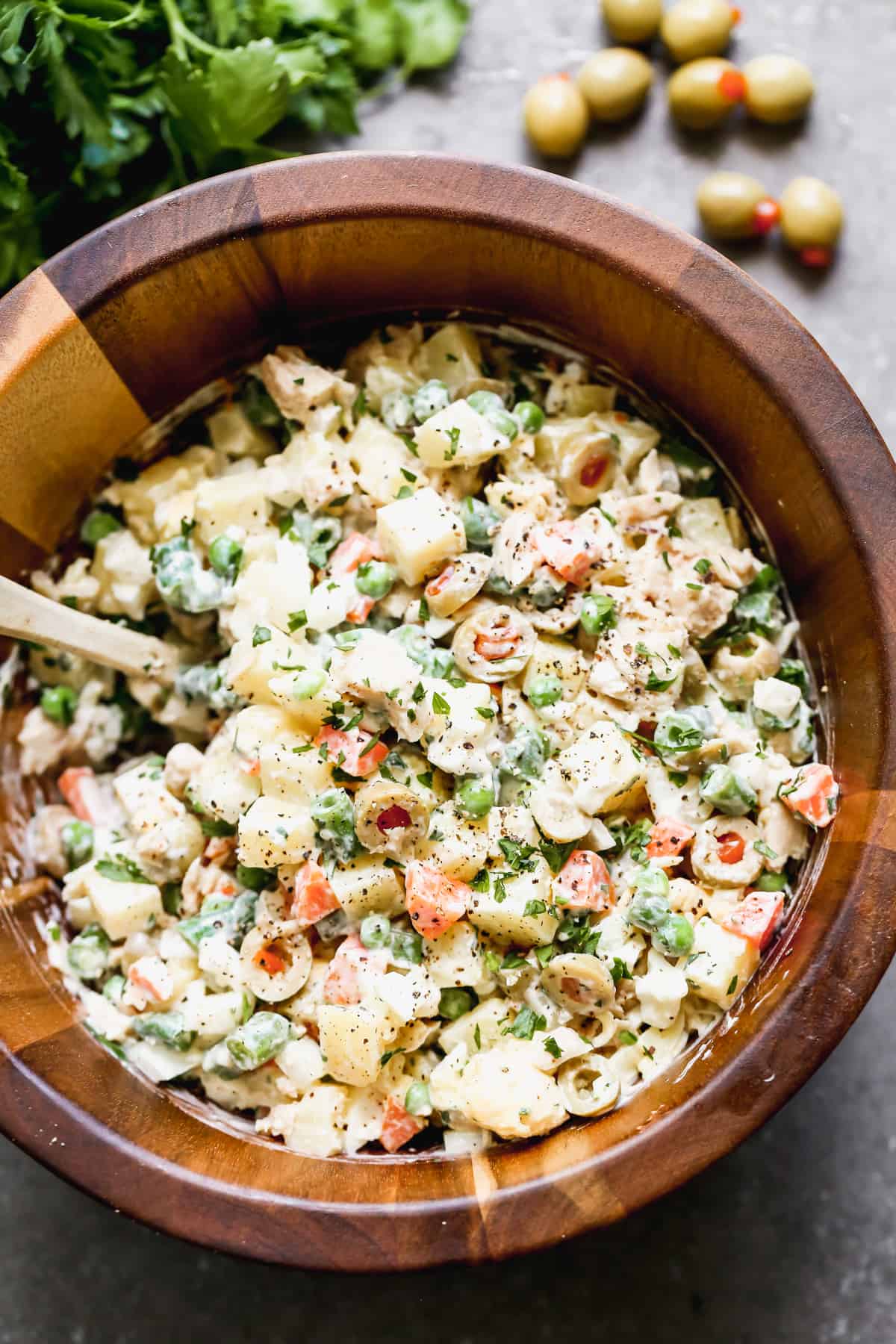 A wooden bowl filled with an easy Ensalada Rusa pasta salad.