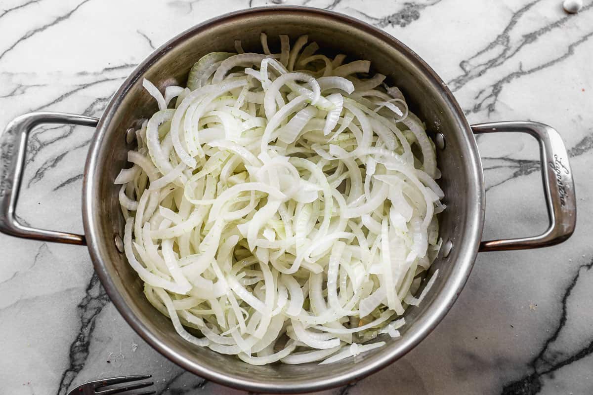 A pot filled with sliced onions to make carmelized onions for an onion burger recipe.