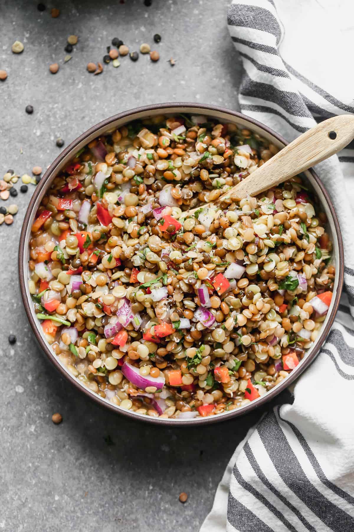 A large bowl filled with Lentil Salad and some fresh chopped vegetables.