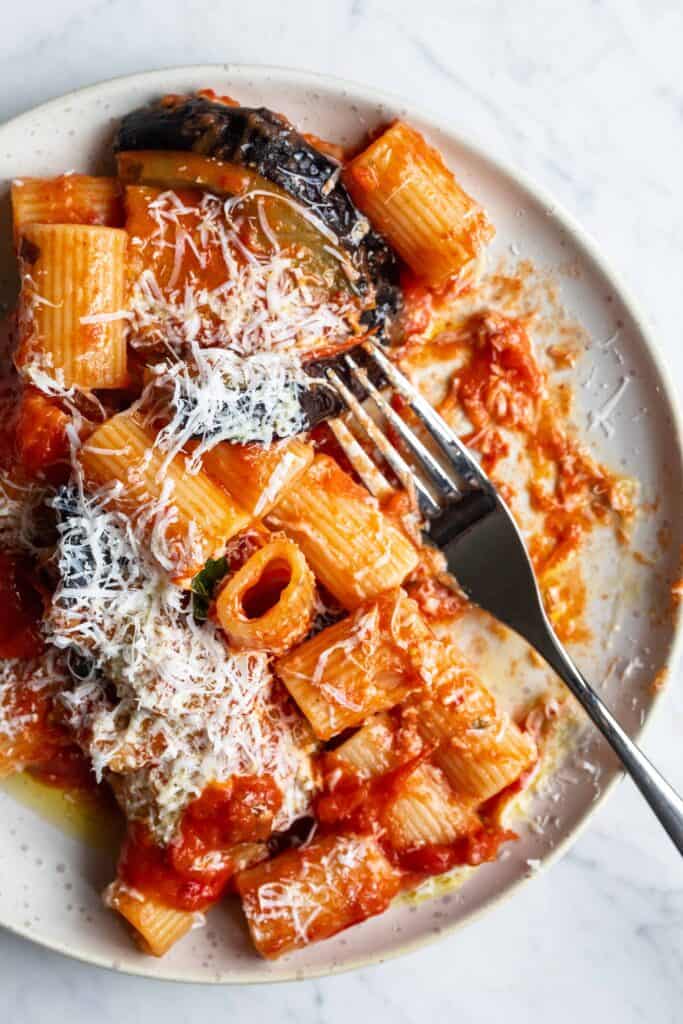 A plate of Pasta Alla Norma with parmesan cheese on top.