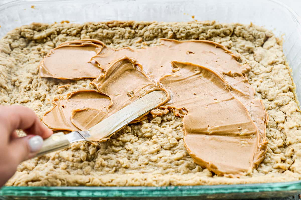 Smooth peanut butter being spread across easy peanut butter bars.