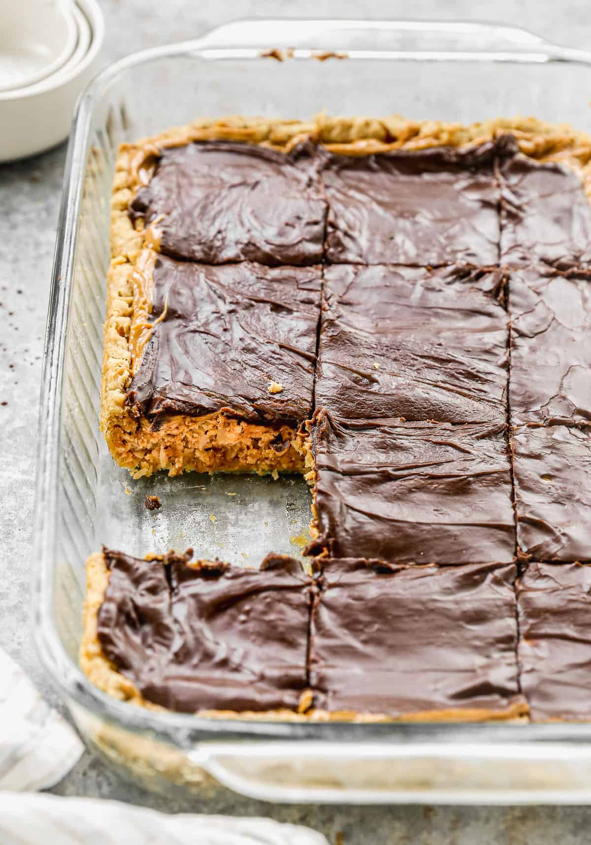 Chewy peanut Butter bars cut into bars in a glass dish and one of them removed. 