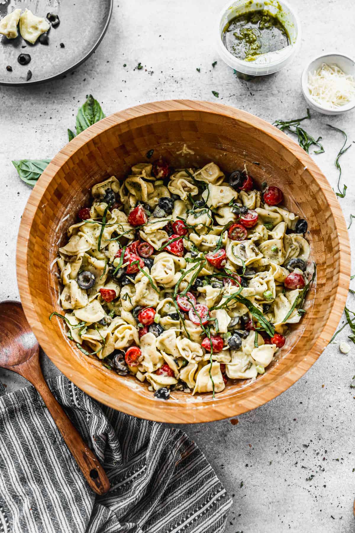 A wooden bowl filled with creamy Pesto Tortellini salad.