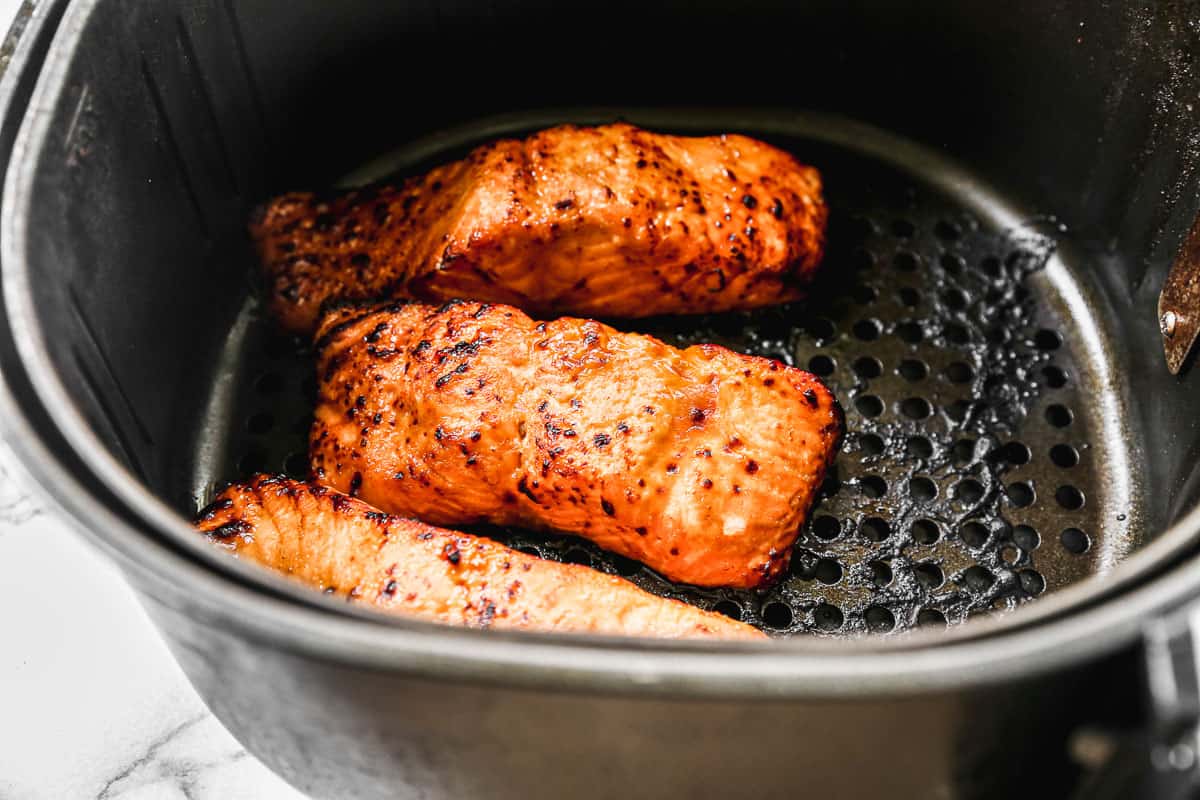 Three salmon fillets in an air fryer basket, just cooked to perfection for the best salmon bowl recipe.