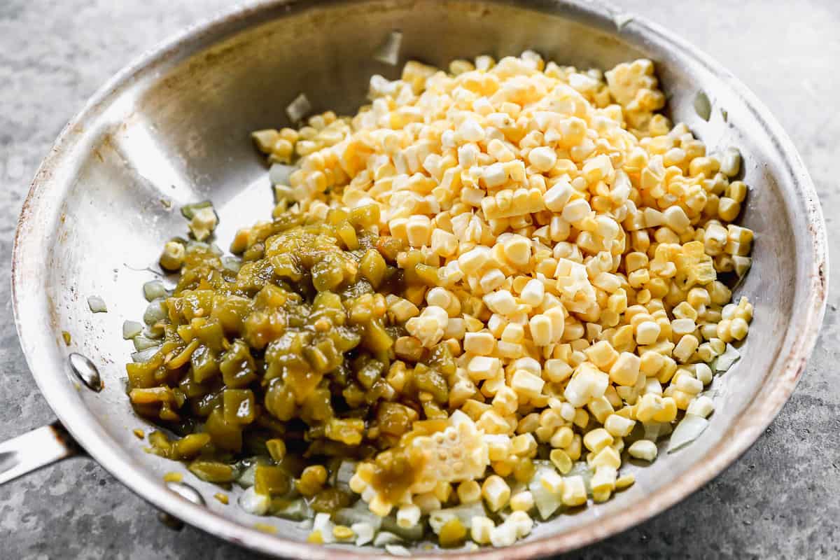 Diced onion, corn, and diced green chiles being cooked in a pan to make the best Street Corn Dip recipe.