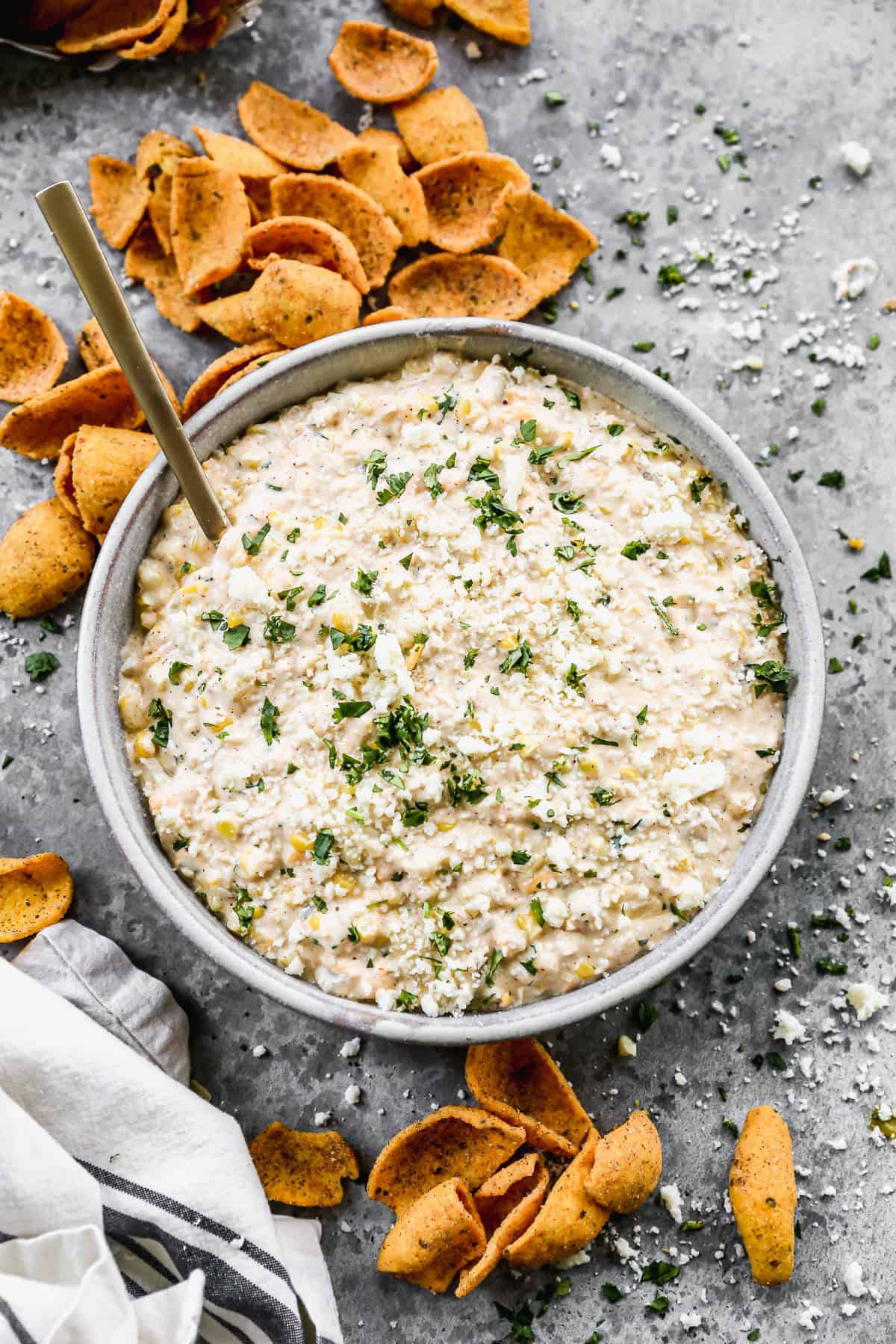 An easy Mexican Street Corn Dip recipe in a large bowl with frito chips scattered around it, ready to enjoy.
