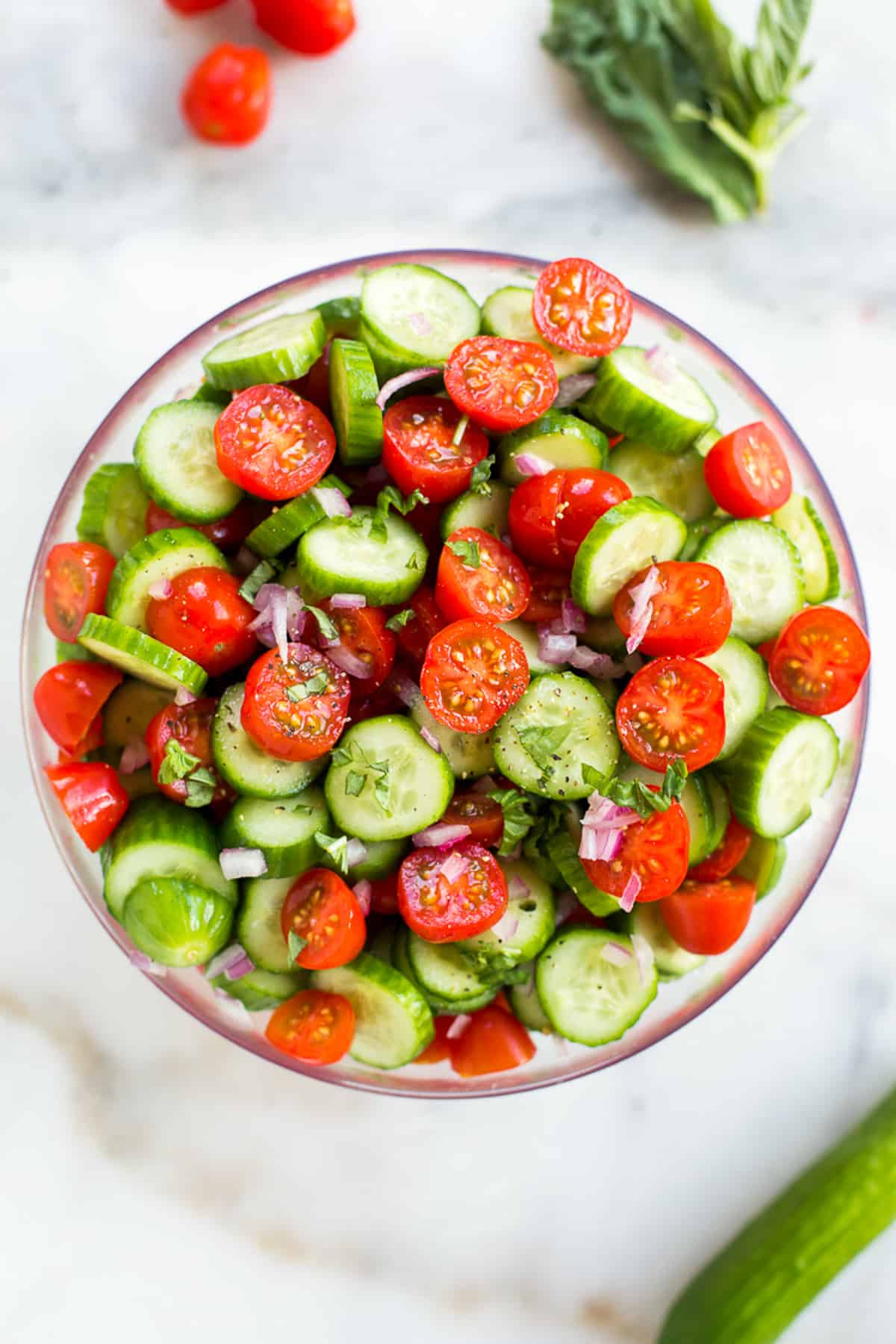 An easy cucumber and tomato salad with fresh vegetables in a glass bowl.