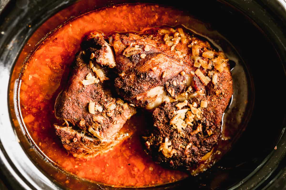 A cooked pork shoulder roast in a slow cooker to make carnitas tacos.