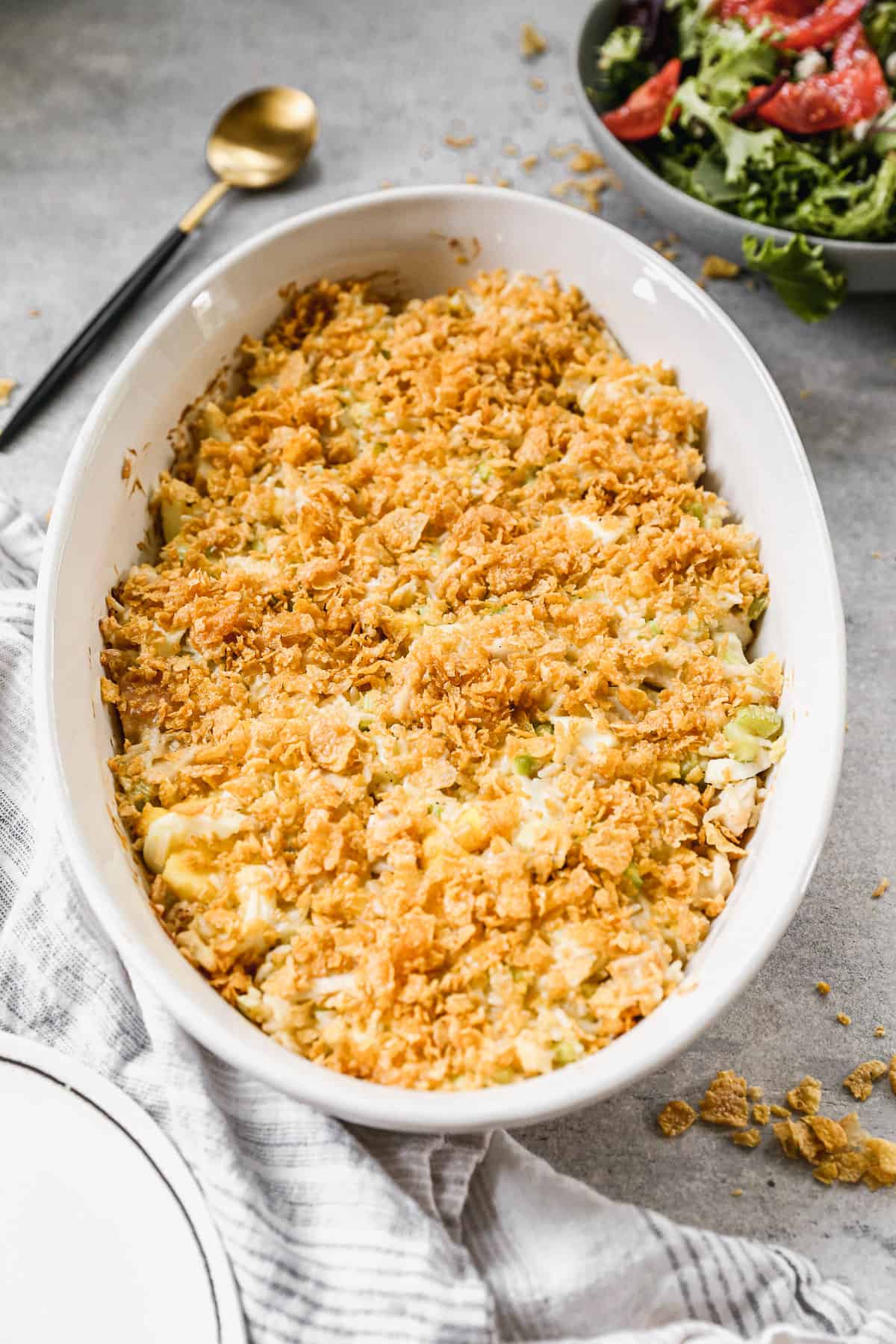 An easy Chicken Casserole recipe in a white oval baking dish, topped with a corn flake topping.