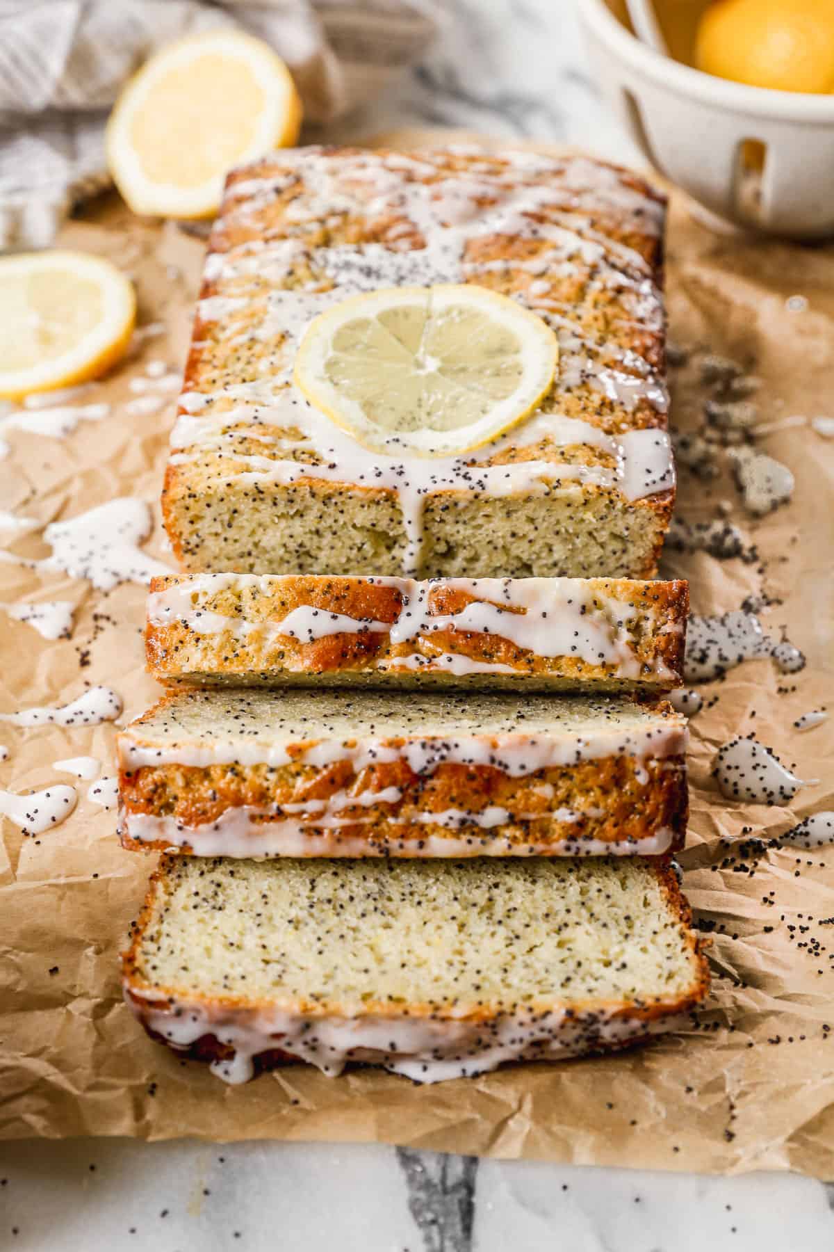 A loaf of the best lemon poppy seed bread recipe with a lemon glaze on top, and a few slices cut.