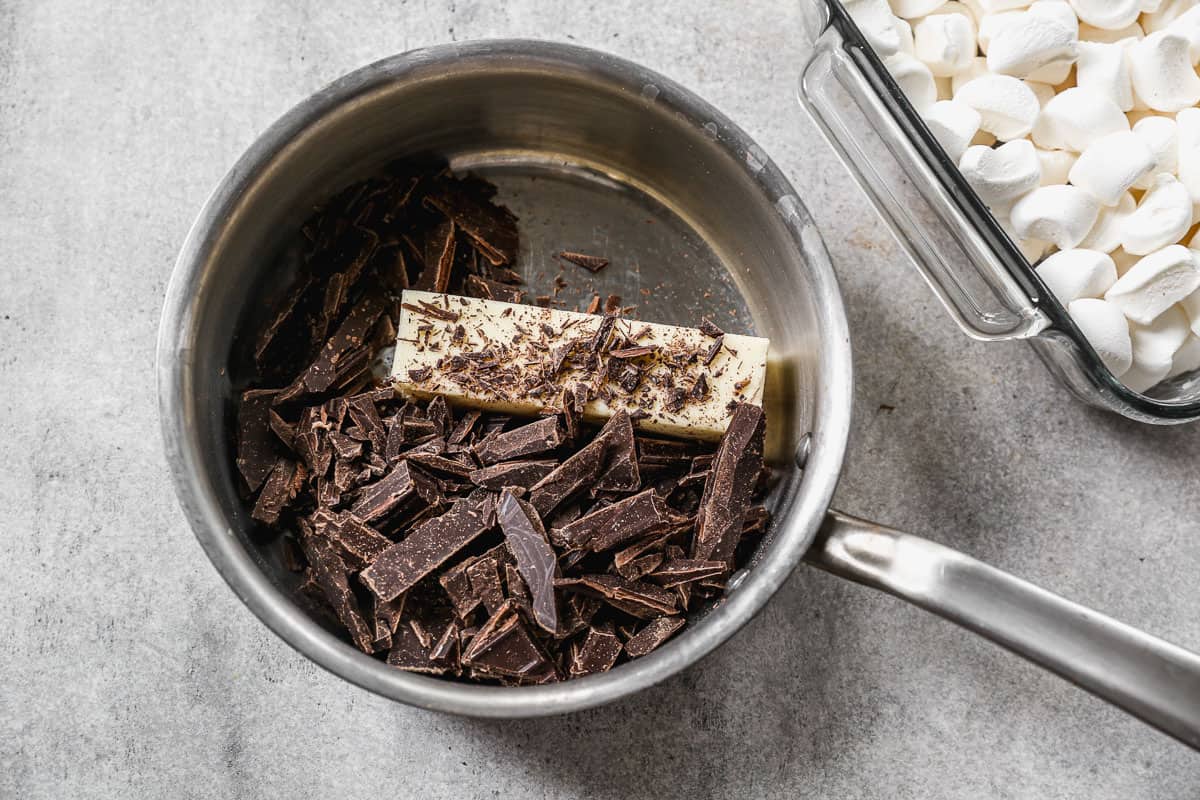 A stainless steel saucepan with chocolate chunks and a square of butter to melt for the best Rocky Road recipe.