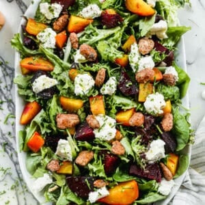 A roasted Beet Salad on a bed of mixed greens with beets, walnuts, and whipped goat cheese.