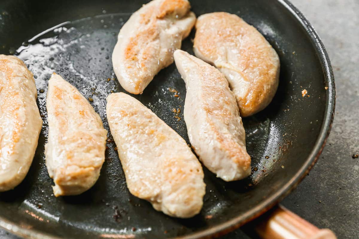 Chicken Tenders being cooked in a pan until golden.
