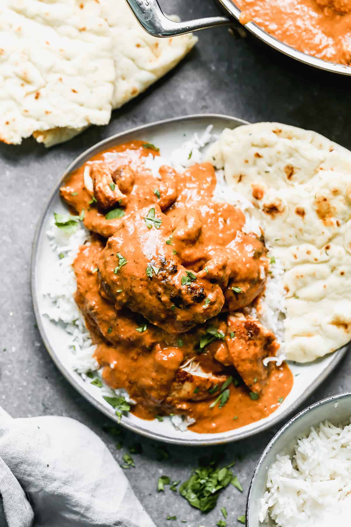 Chicken Tikka Masala on a bed of rice with naan next to it, ready to enjoy.
