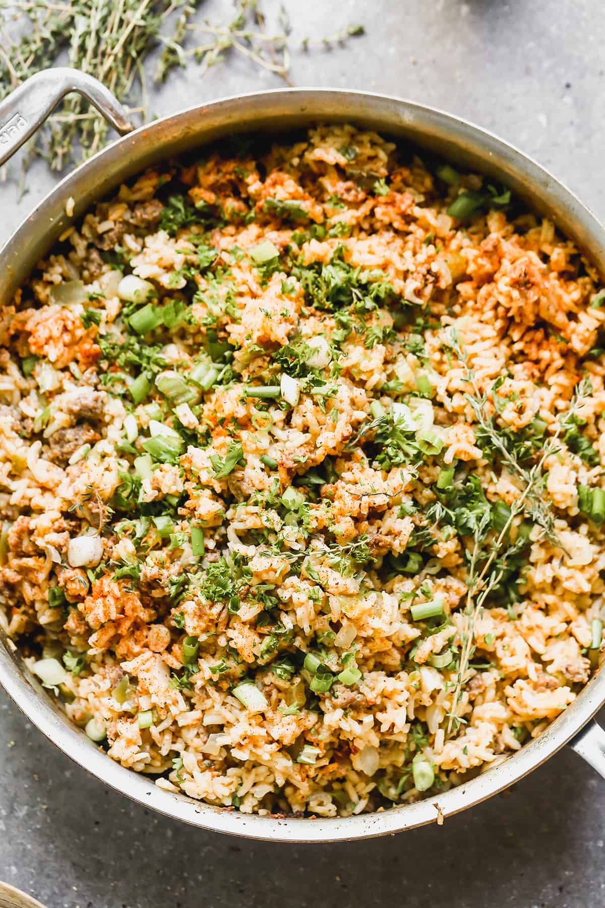 Cajun rice in a large pan, garnished with green onion and parsley.