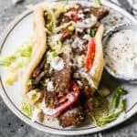 A homemade Gyro recipe with gyro meat wrapped in a fresh pita and topped with vegetables and tzatziki sauce.